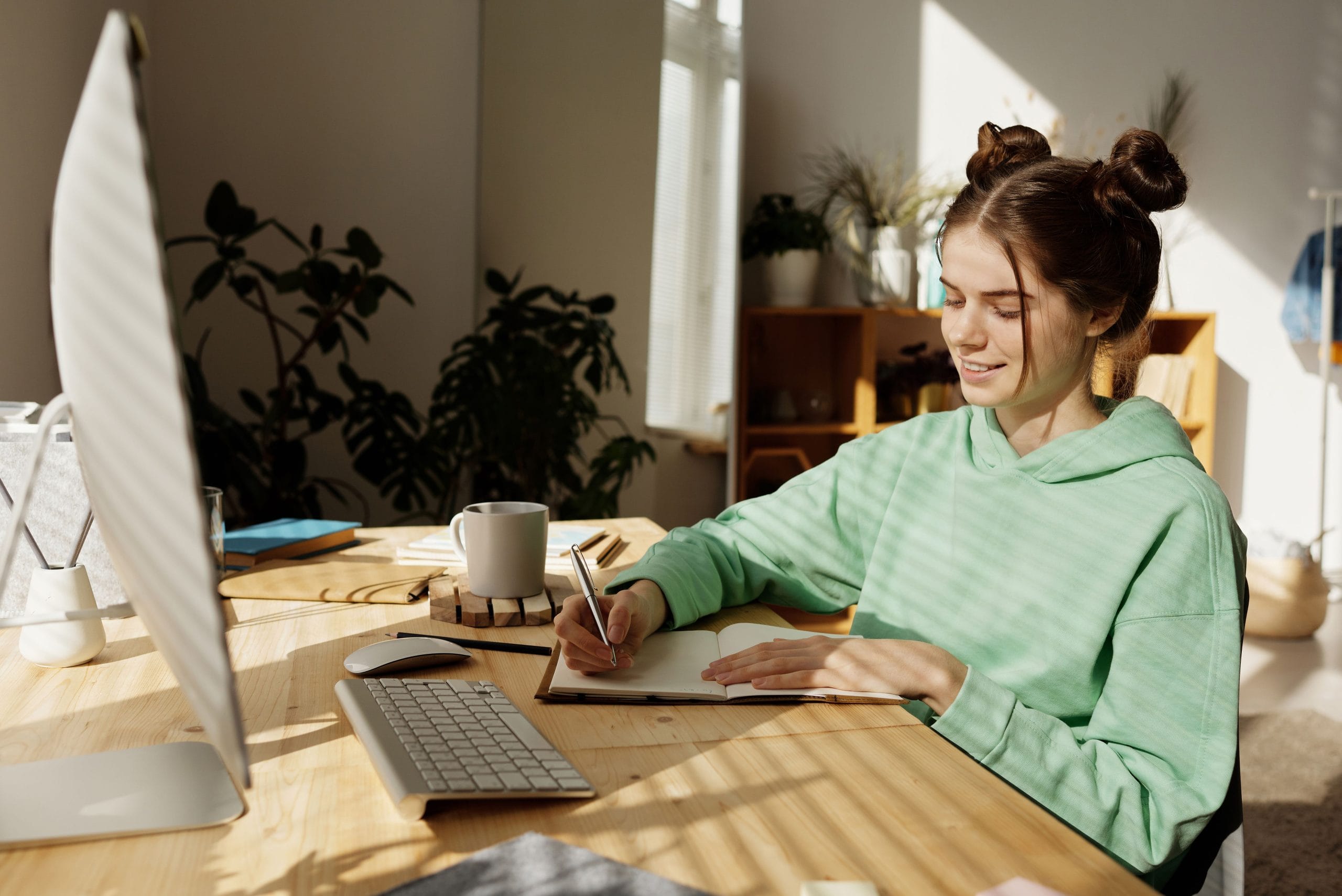 Person writing in a journal at a desk, reflecting on personal goals and practicing healthy boundary setting in a calm home workspace.