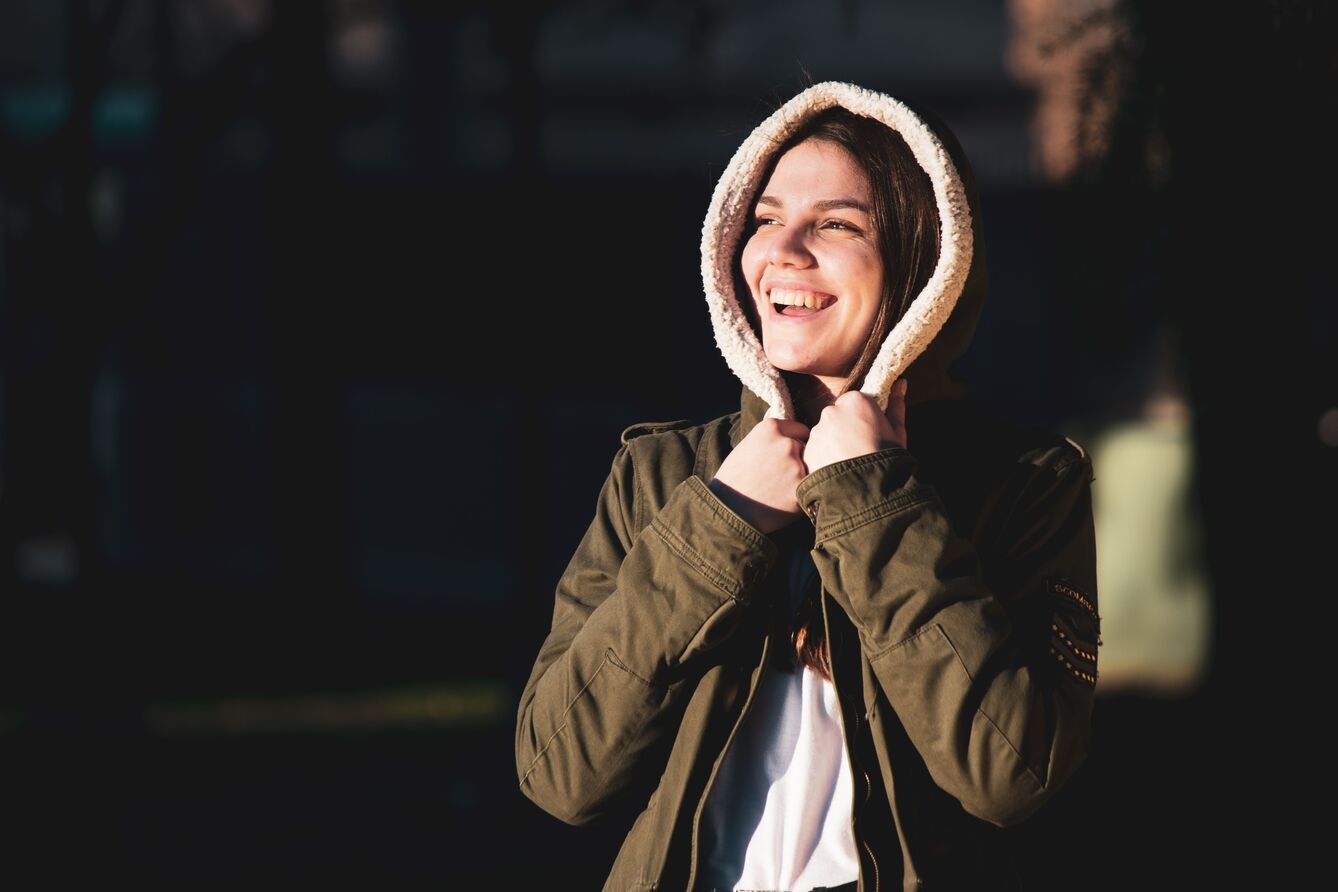A cheerful woman in warm clothing enjoying a sunny day.