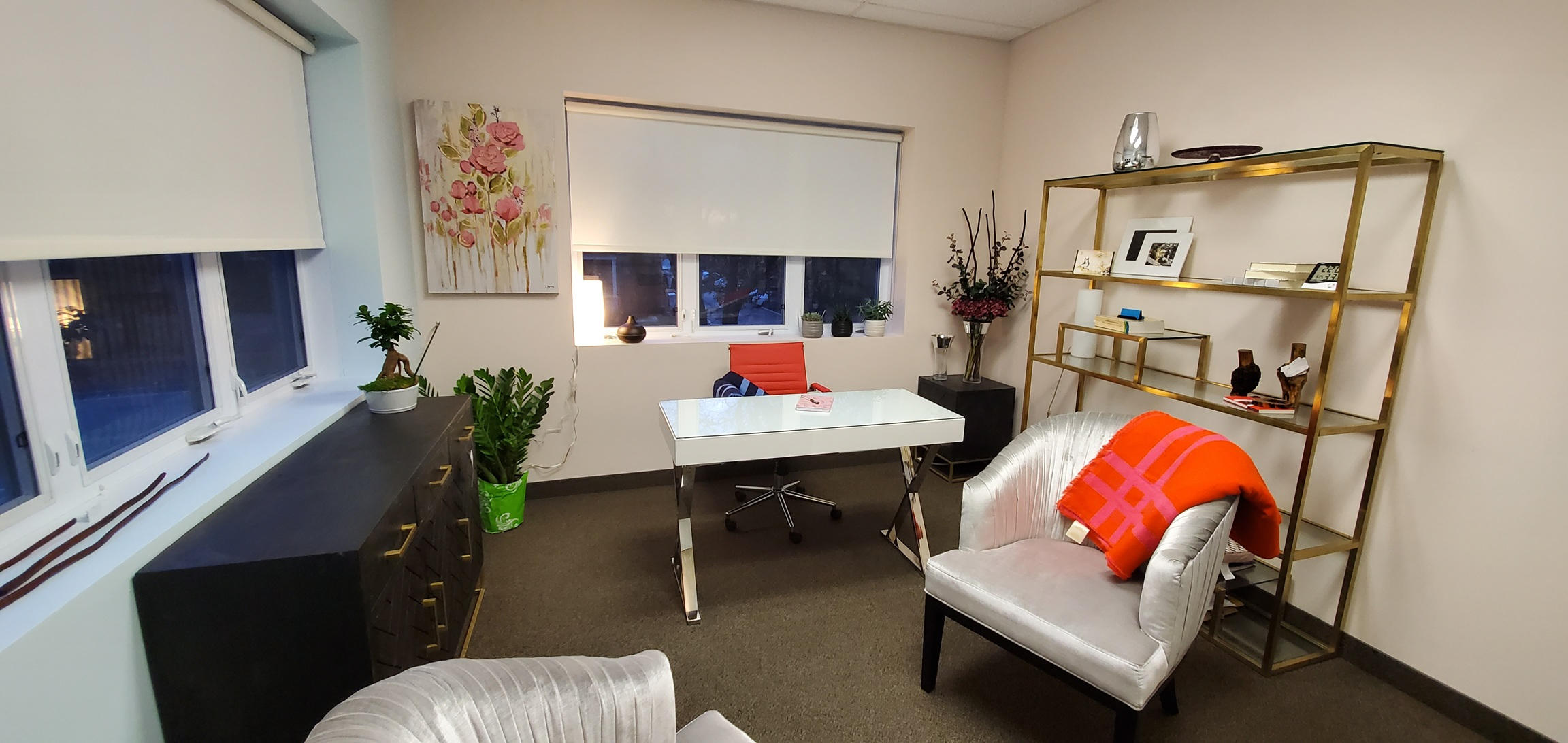 Modern office space with a white desk, elegant chairs, and decorative plants