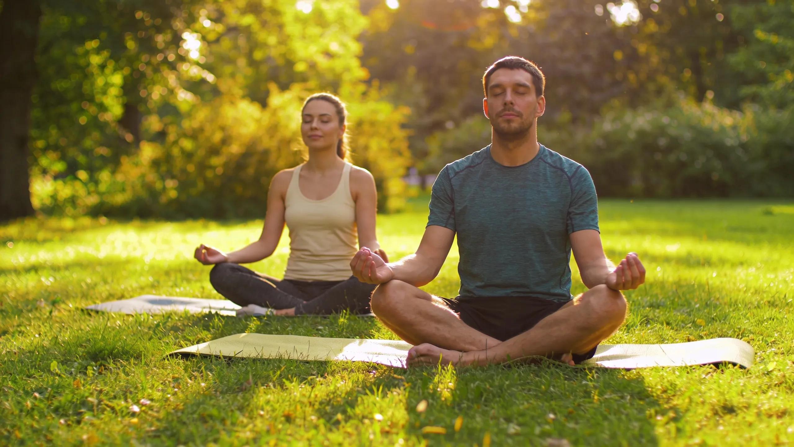 Couple practicing mindfulness together in a tranquil park, showcasing stress-management techniques.